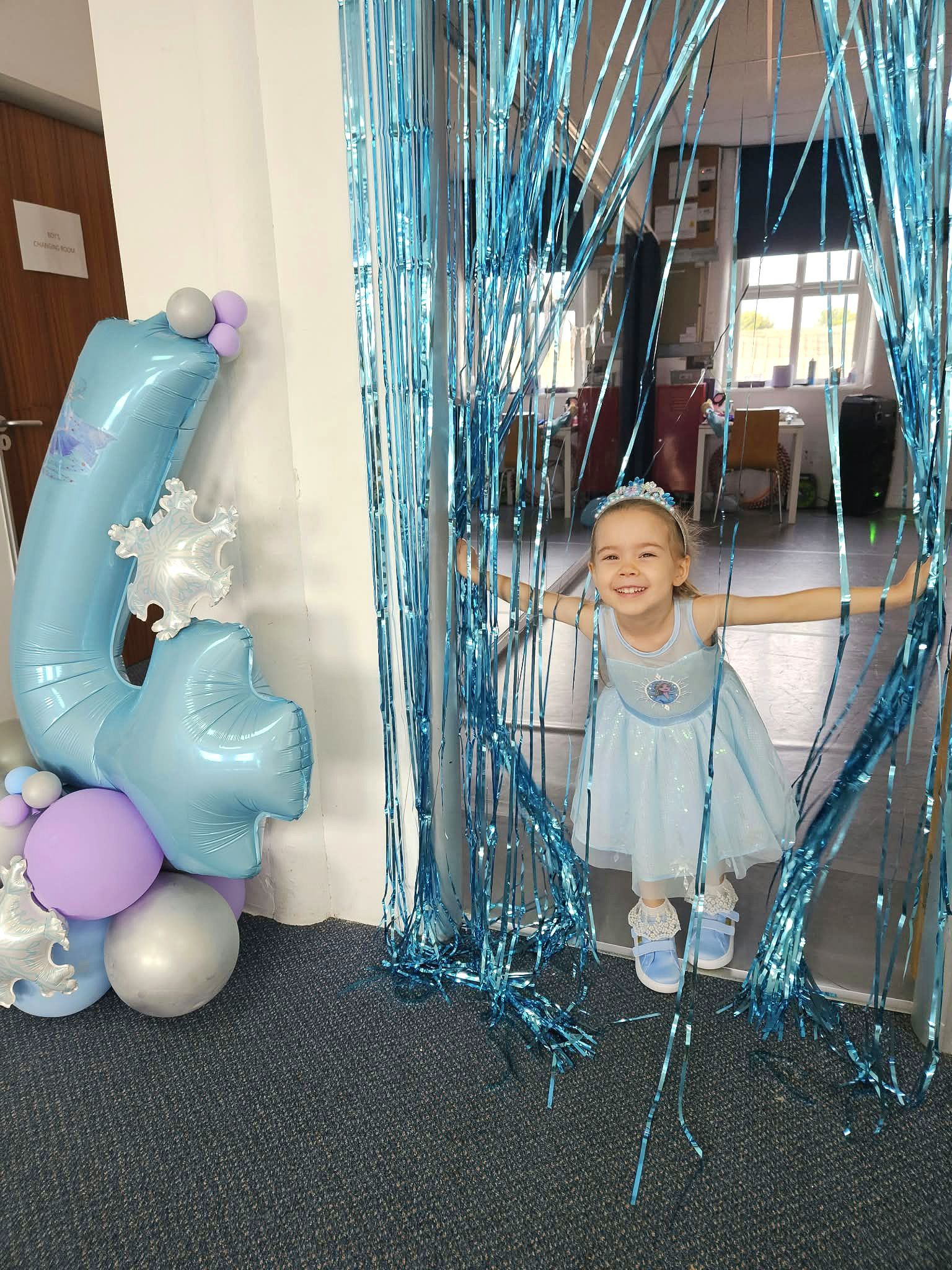 A birthday child celebrating at Kay Academy with blue balloons and party decorations